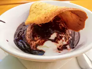 Postre de helado con chocolate caliente y teja de almendra