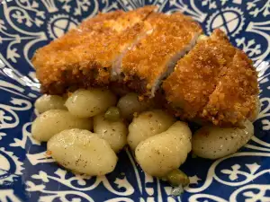 Filetes de pavo empanados sobre cama de ñoquis