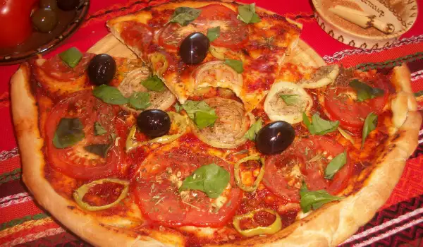 Pizza vegetariana con tomate, aceitunas y albahaca