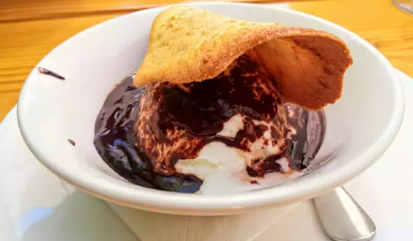 Postre de helado con chocolate caliente y teja de almendra